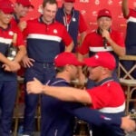 Bryson DeChambeau and Brooks Koepka hug in front of their Ryder Cup teammates following the U.S. victory