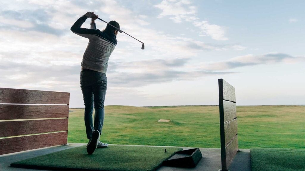 a golfers hits a ball on the driving range