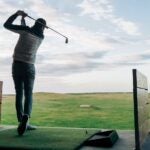 a golfers hits a ball on the driving range
