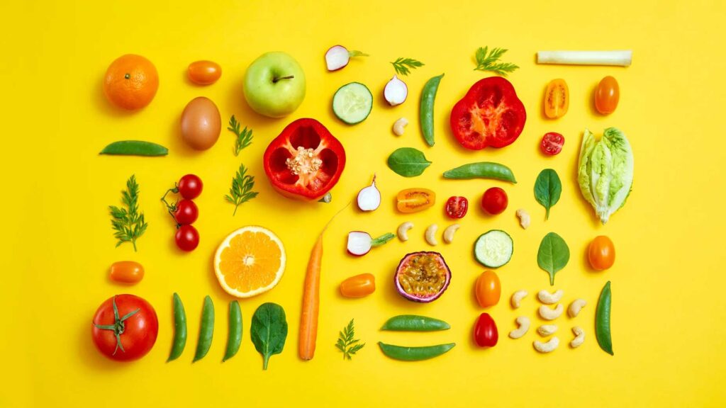 Fruits and vegetables laid on a yellow background