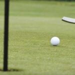 a golfer rolls a putt on a golf green