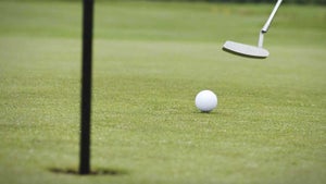a golfer rolls a putt on a golf green