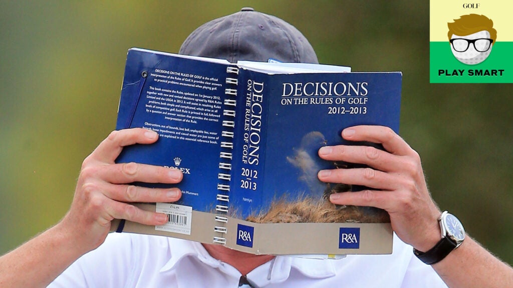 Man reads blue golf rules book as he holds it in front of his face