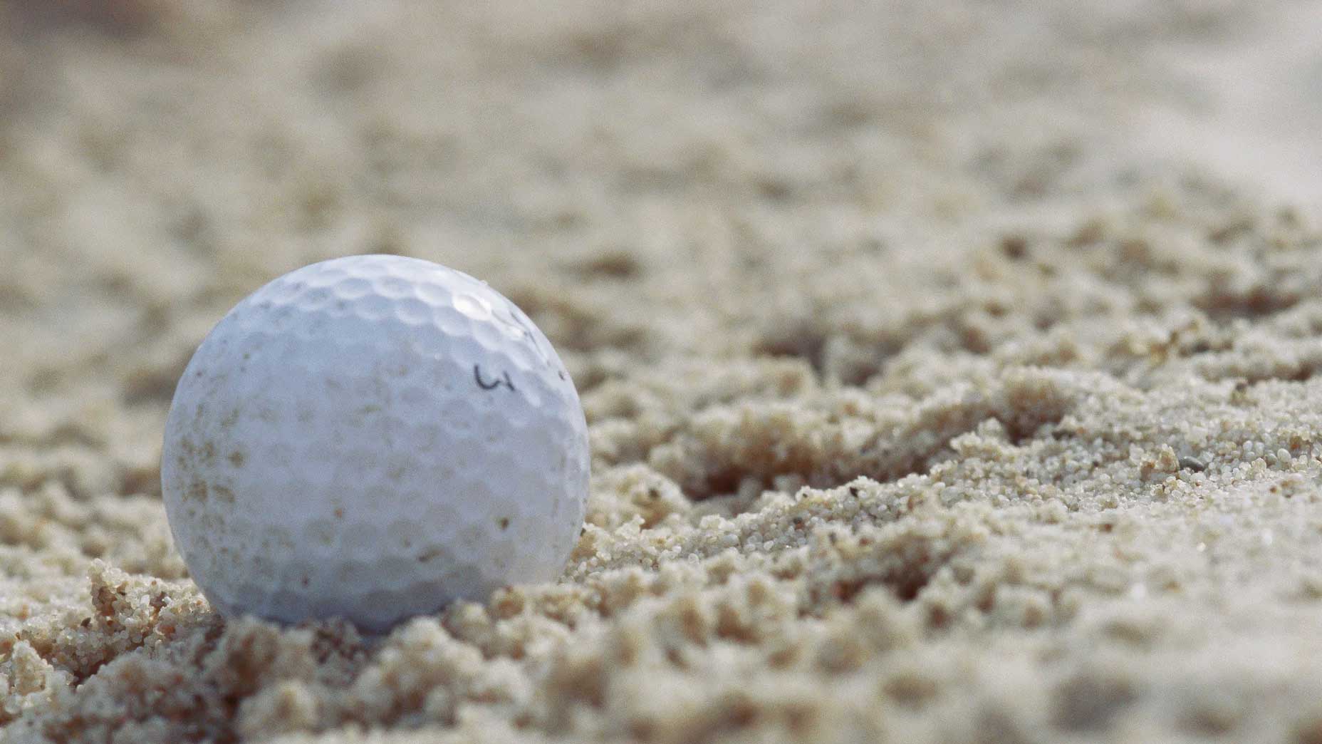 golf ball sitting in sand trap on golf course