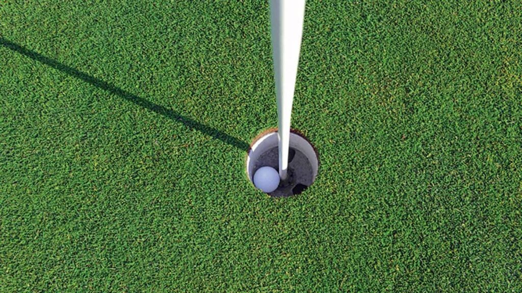 A golf ball in a golf hole.