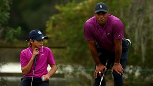 Tiger Woods and Charlie Woods read putt on golf green at PNC Championship