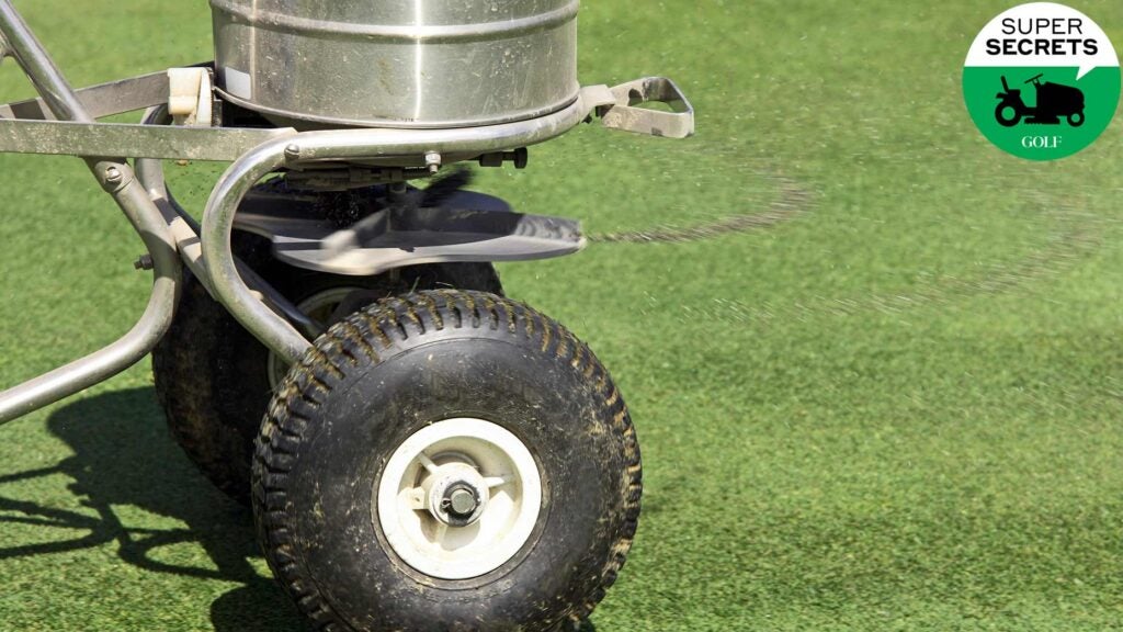 A worker spreads fertilizer on a golf course.