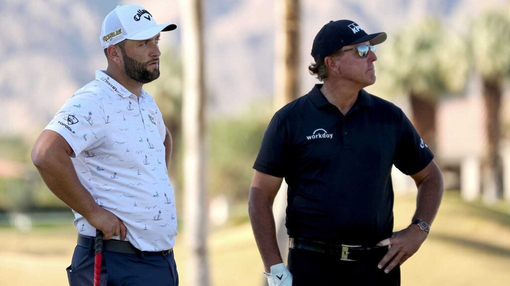 Jon Rahm and Phil Mickelson stand on course during 2022 American Express