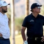 Jon Rahm and Phil Mickelson stand on course during 2022 American Express