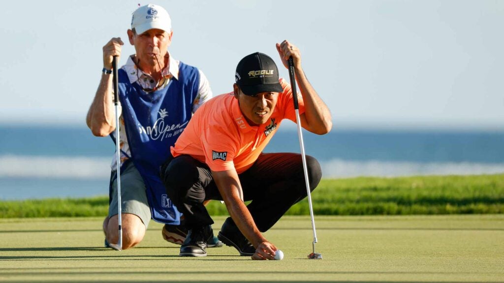 Kevin Na and his caddie line up putt on golf green at 2022 Sony Open