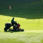 A man mows a golf green.
