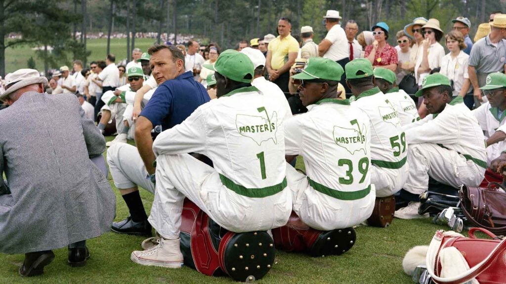 Arnold Palmer looks over his shoulder as he sits with a group of caddies during the 1965 Masters.
