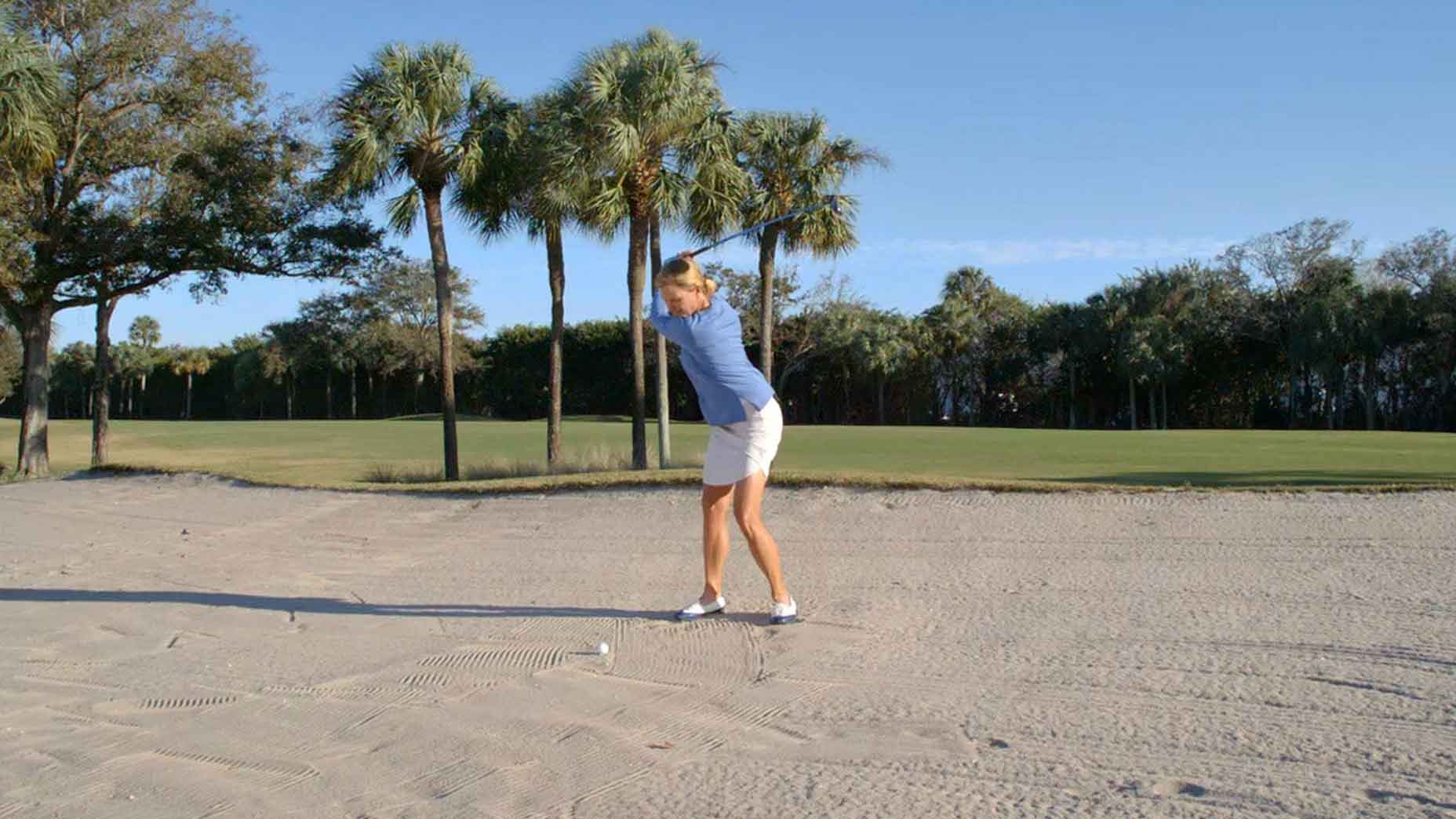 Golf instructor Kellie Stenzel hits bunker shot on golf course