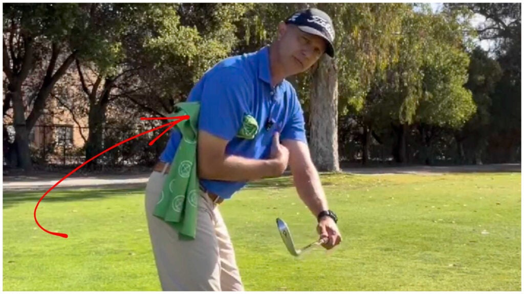 Golf instructor demonstrates drill with towel