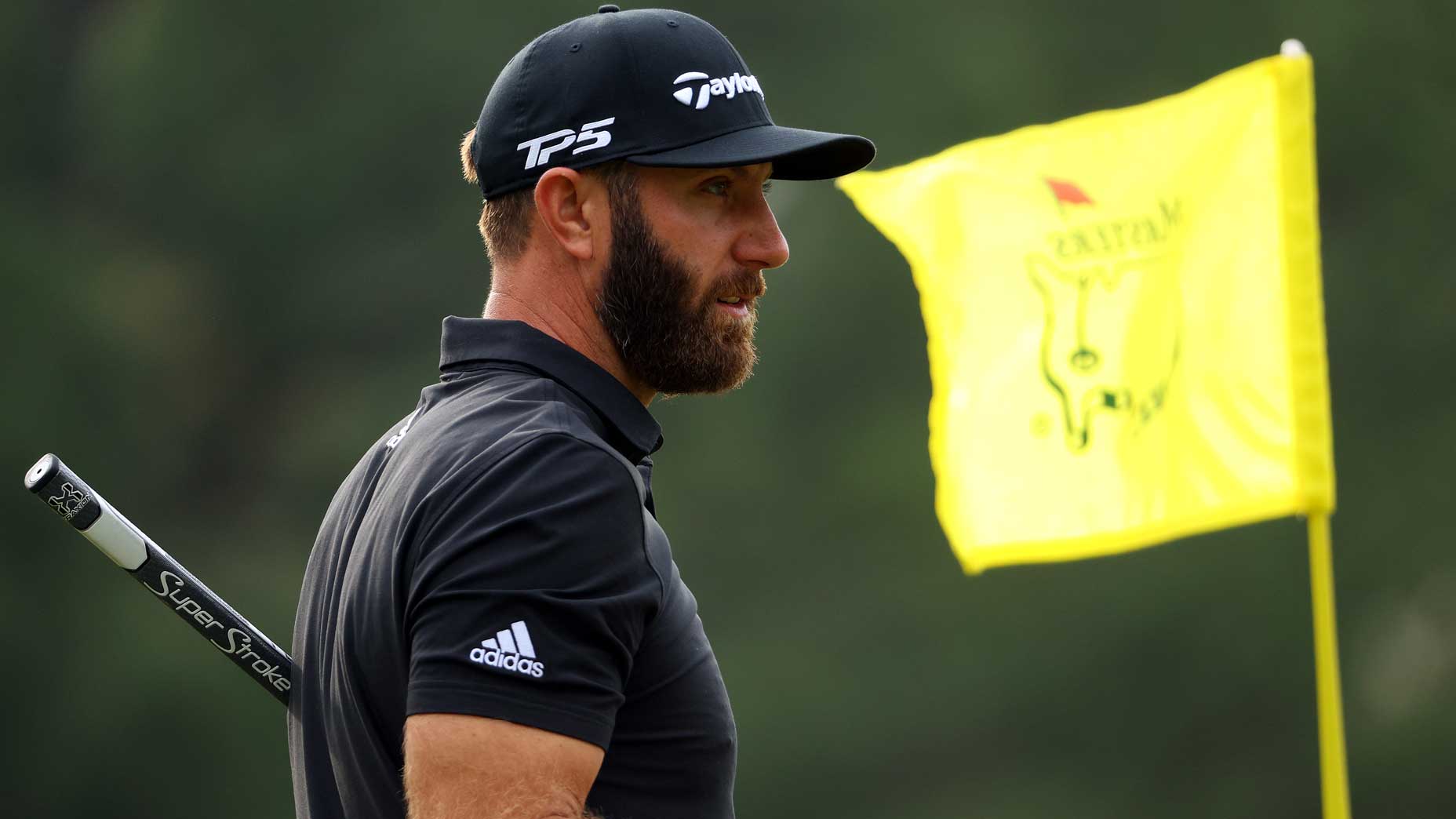 Dustin Johnson looks into distance next to Masters pin flag at 2022 Masters