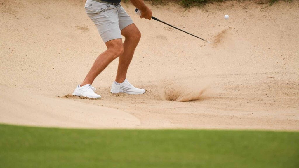 man hits shot out of bunker