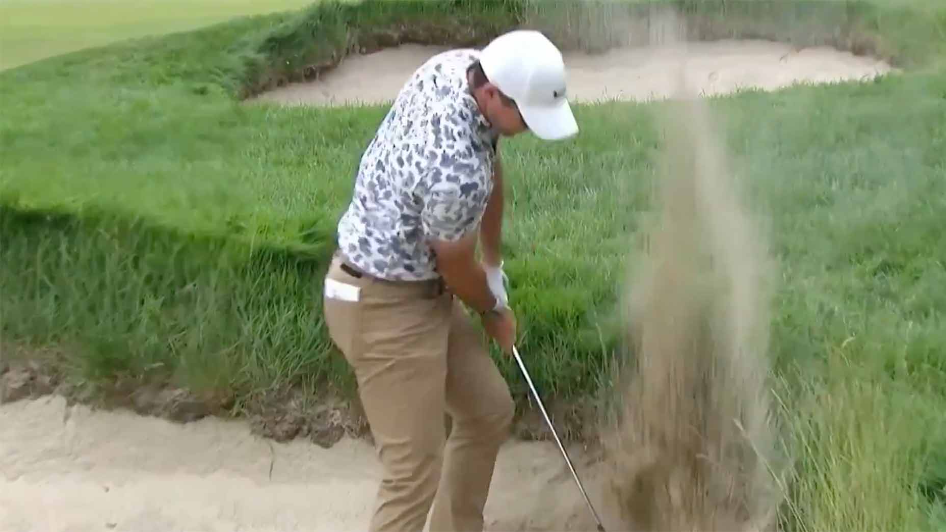 Rory Mcilroy sweeps the sand at the US Open on Thursday.