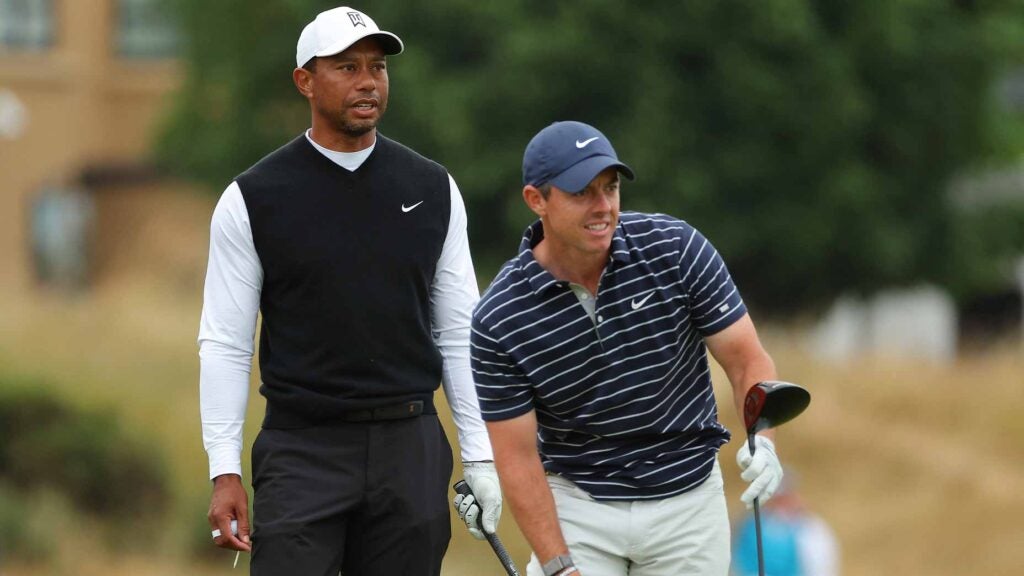 tiger woods stands behind rory mcilroy