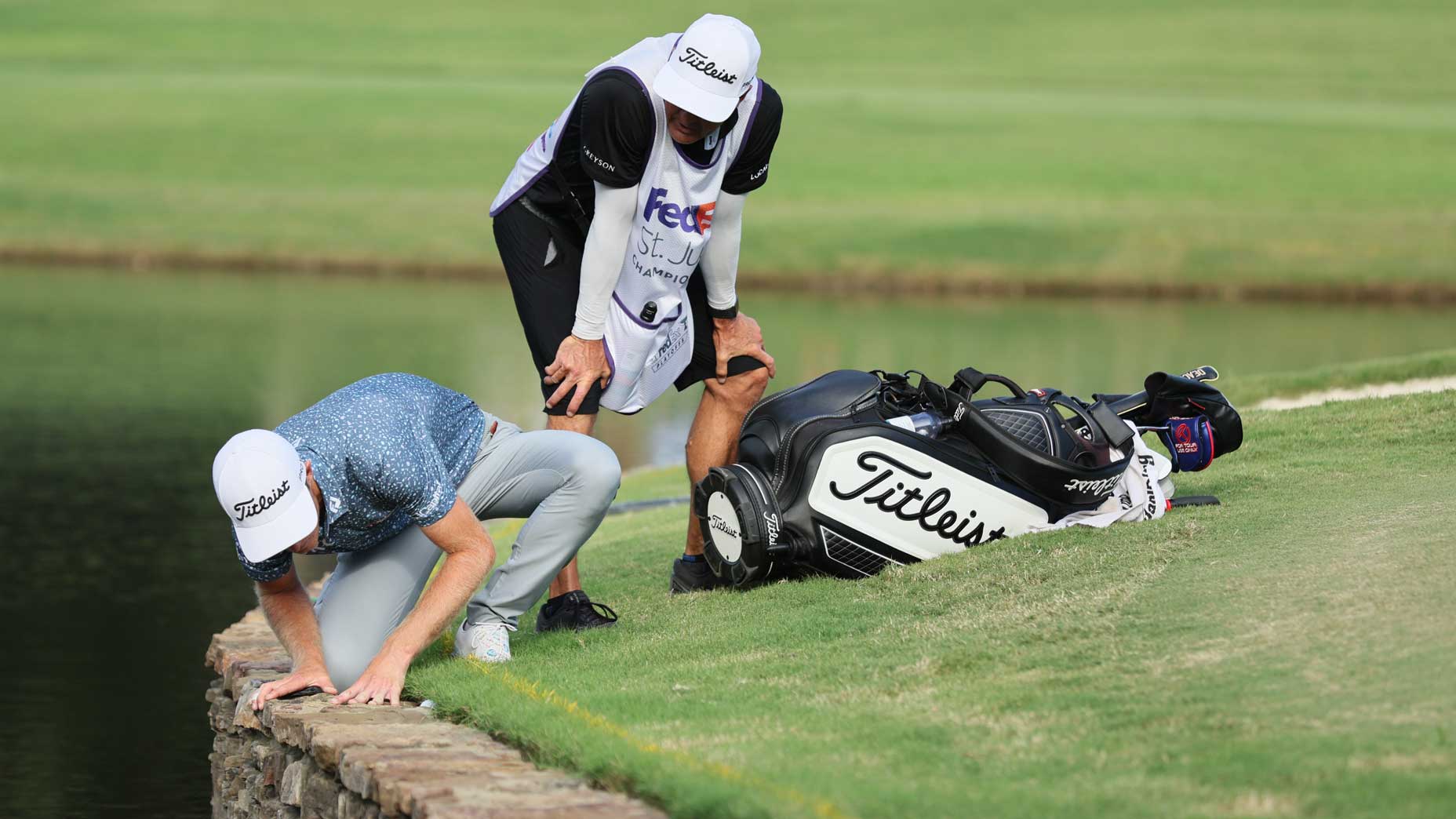 Will Zalatoris looks at his golf ball nestled between a stone wall and the turf.