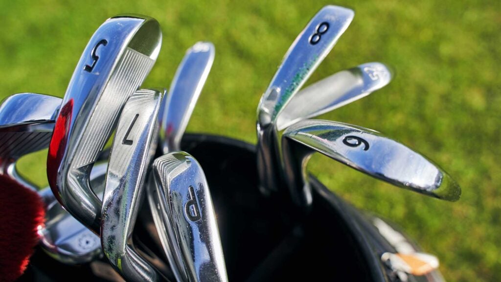 Close up of different types of stainless steel golf clubs with numbers placed in a golfer bag