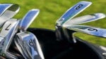 Close up of different types of stainless steel golf clubs with numbers placed in a golfer bag