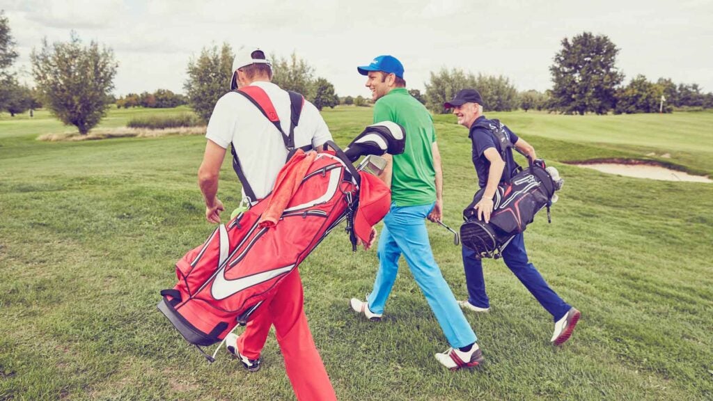 three men walk on a golf course
