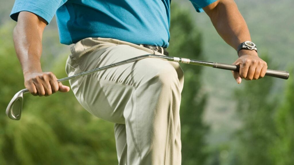 Golfer breaking golf club over his knee