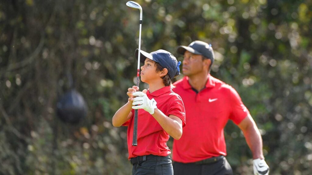 Charlie Woods hits shot while Tiger Woods watches at PNC Championship