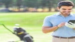 Smiling golfer talking on his mobile phone on the course standing next to his bag with golf clubs.