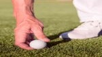 hand placing golf ball