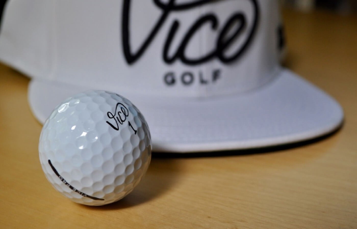 Vice golf logo hat and Vice golf ball on a table