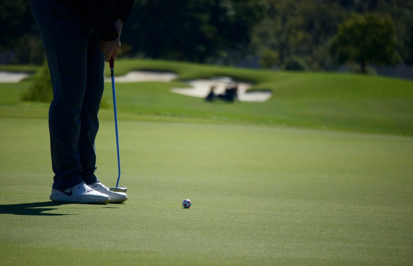 Person standing on the green in Nike golf shoes