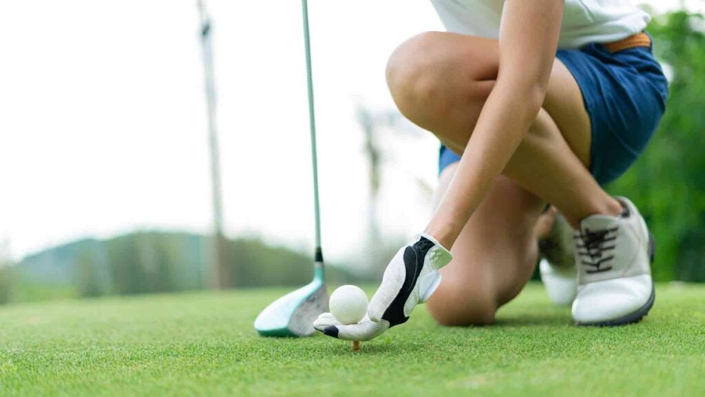 Woman teeing up ball