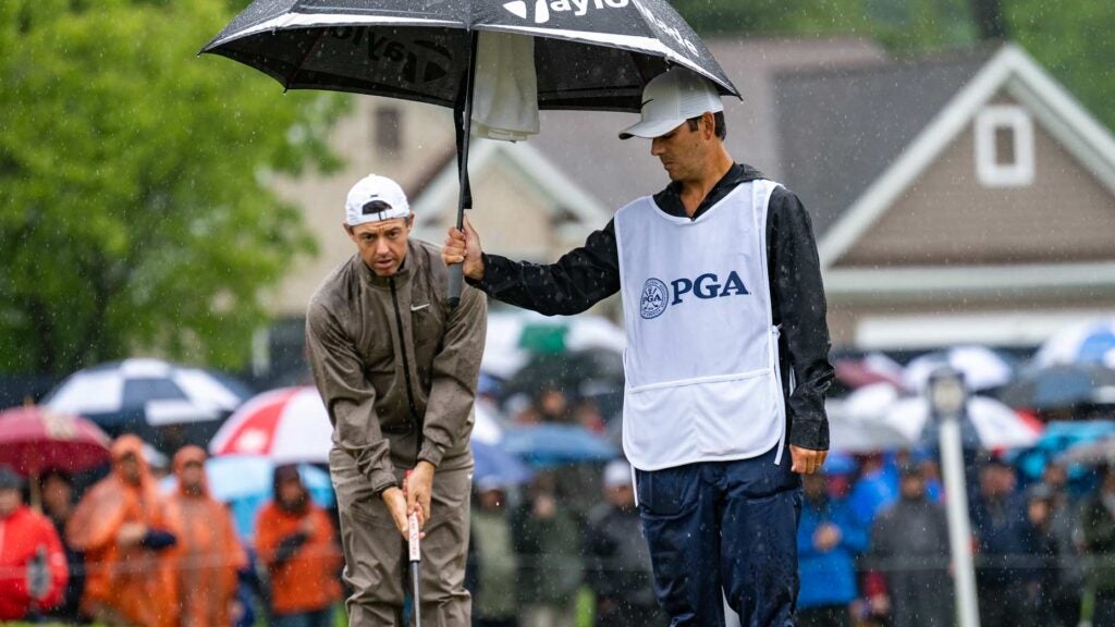 Harry Diamond holds an umbrella over Rory McIlroy's golf ball on the 4th green during the third round of the 2023 PGA Championship.