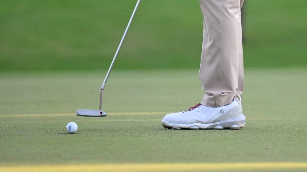 golfer hits putt on putting green