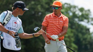 Rickie Fowler hands a club to his caddie, Ricky Romano