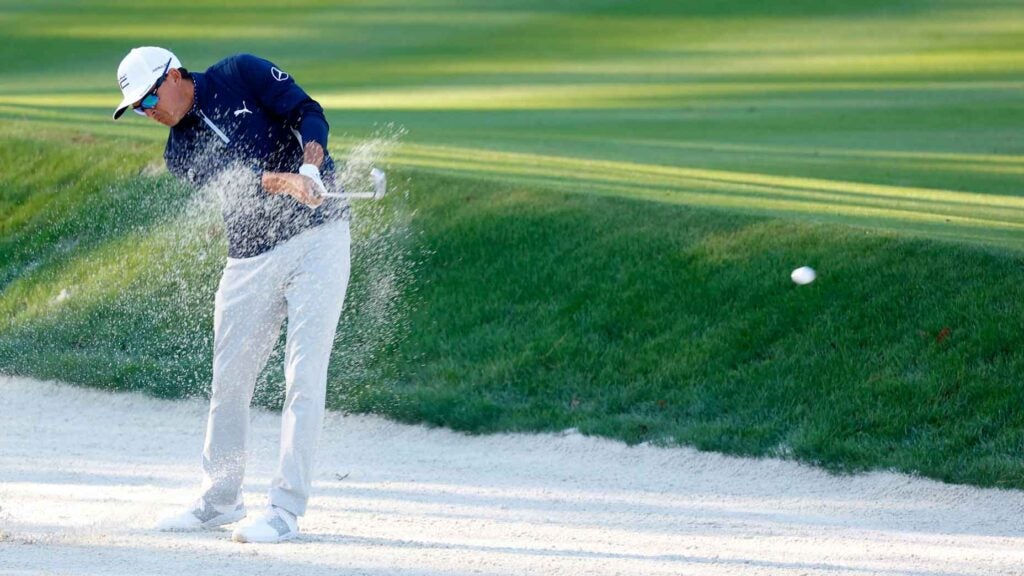 Rickie Fowler hits a shot from a fairway bunker