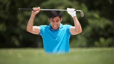 golfers gets angry and holds club over his head