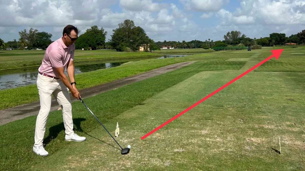 Golf instructor demonstrates driving tip on tee box