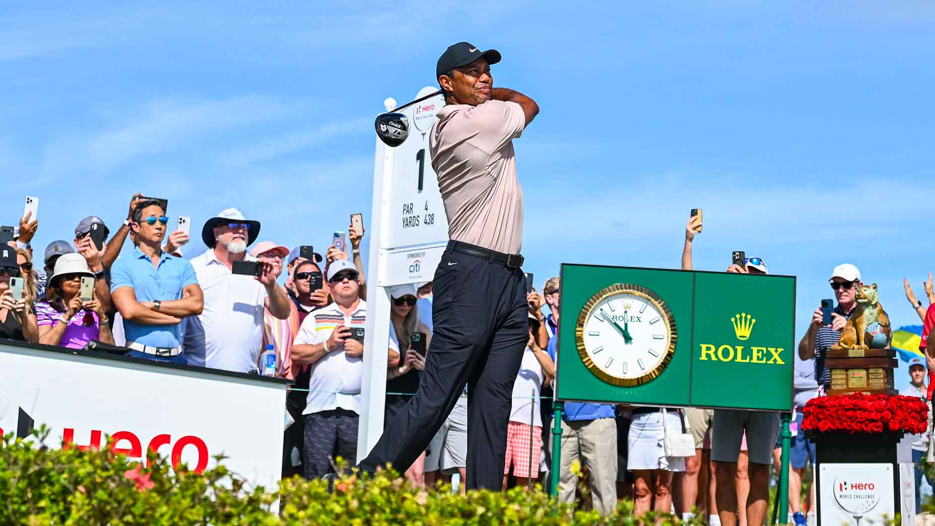 Tiger Woods plays his shot from the first tee in front of the Rolex clock as fans watch during the first round of the Hero World Challenge at Albany Golf Course on November 30, 2023 in Nassau, New Providence, Bahamas.