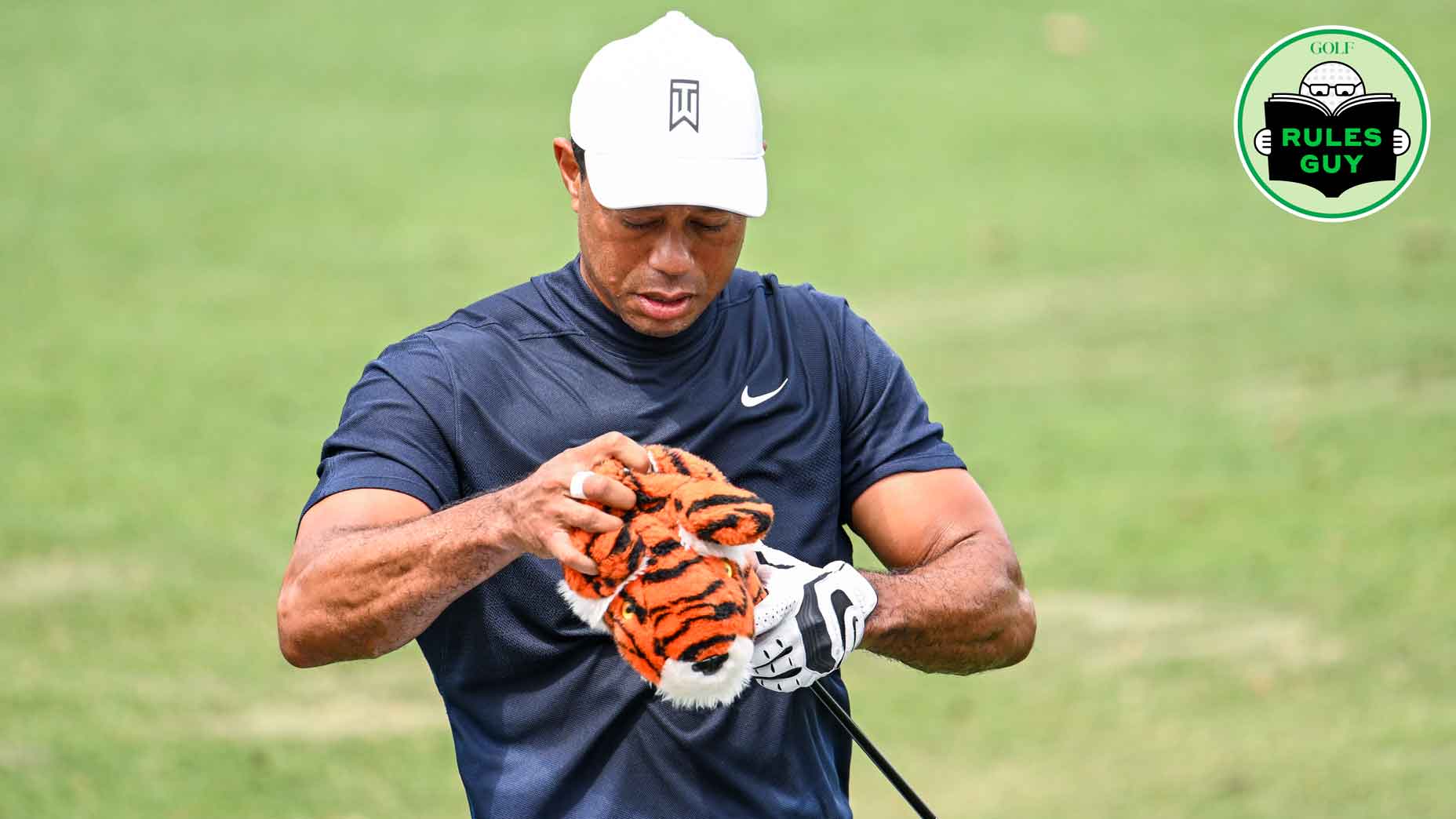 Tiger Woods adjusts the headcover of his driver.