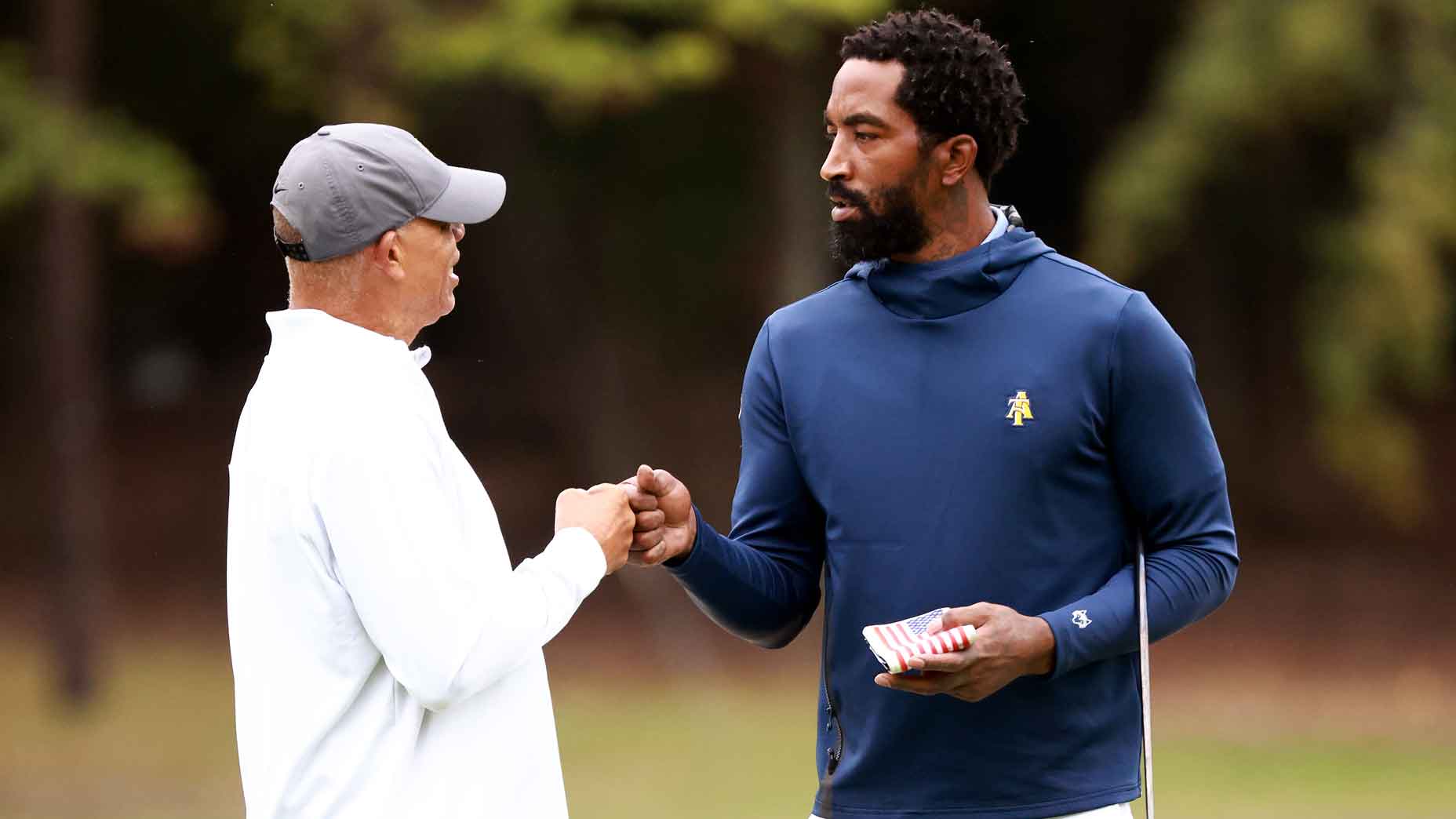 Former NBA player J.R. Smith gets a word of encouragement from head coach Richard Watkins of the North Carolina A&T Aggies during the Phoenix Invitational at Alamance Country Club on October 11, 2021 in Burlington, North Carolina.