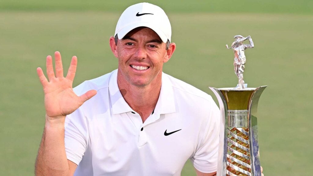 Rory McIlroy holds up five fingers and the Race to Dubai trophy on golf course in Dubai