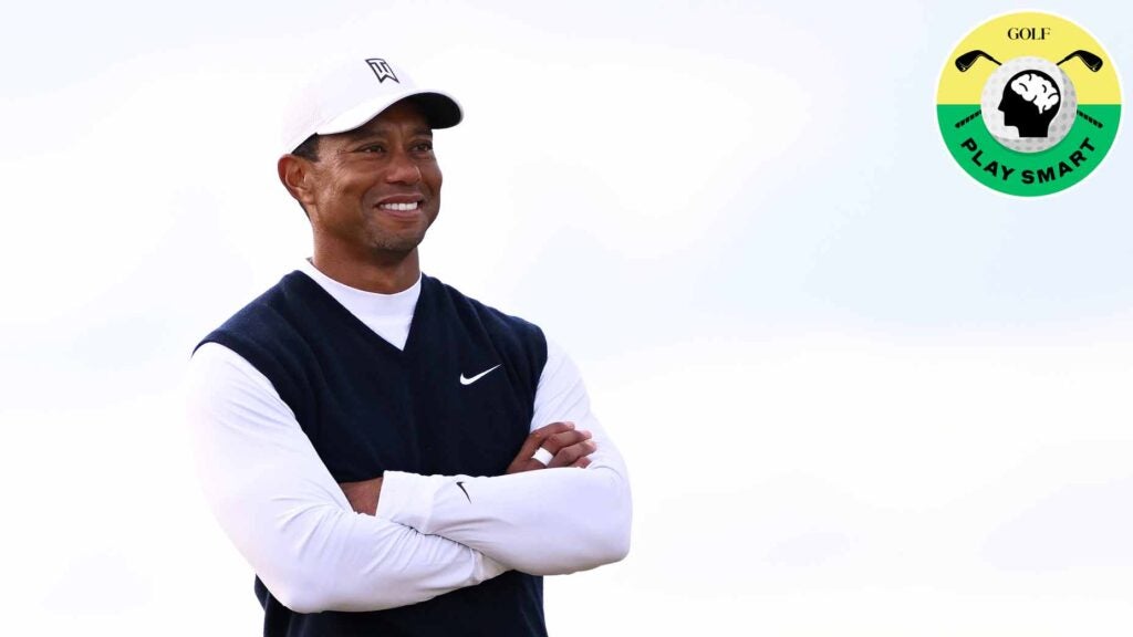 tiger woods smiles while wearing a black vest and white long sleeved shirt