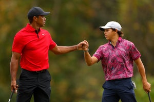 Tiger Woods wearing a red Nike polo and his son Charlie Woods wearing a tropical pink Greyson polo.