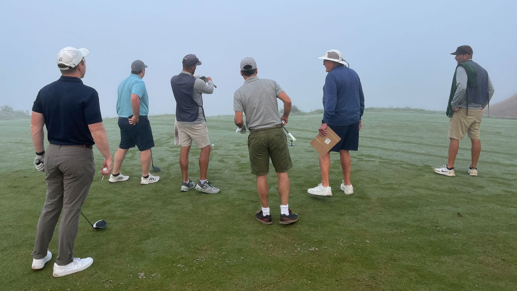 a group of golfers playing streamsong blue in a dense fog