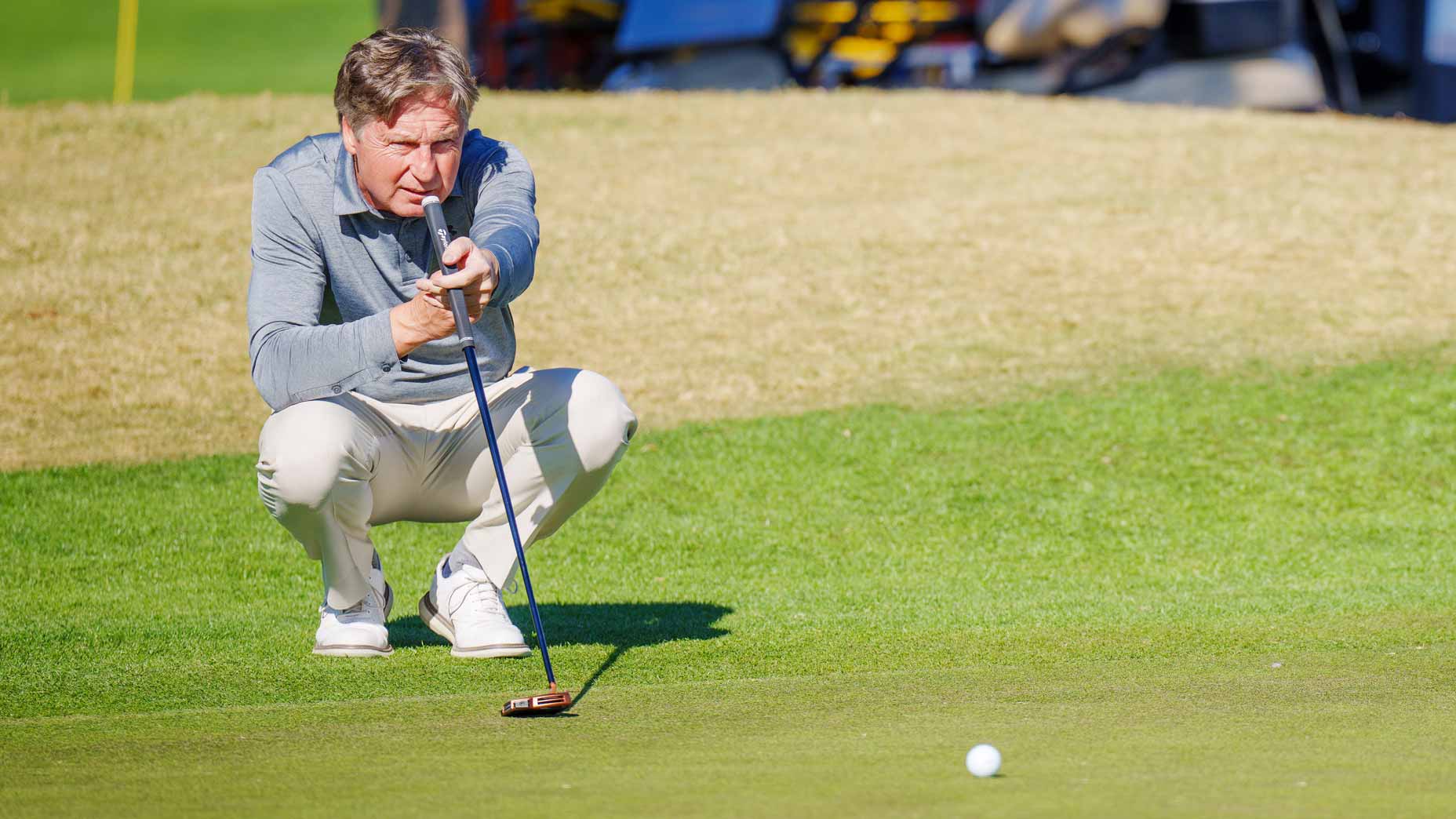 Brandel Chamblee crouches to read a putt on green at 2022 PGA Tour Champions Qualifying event