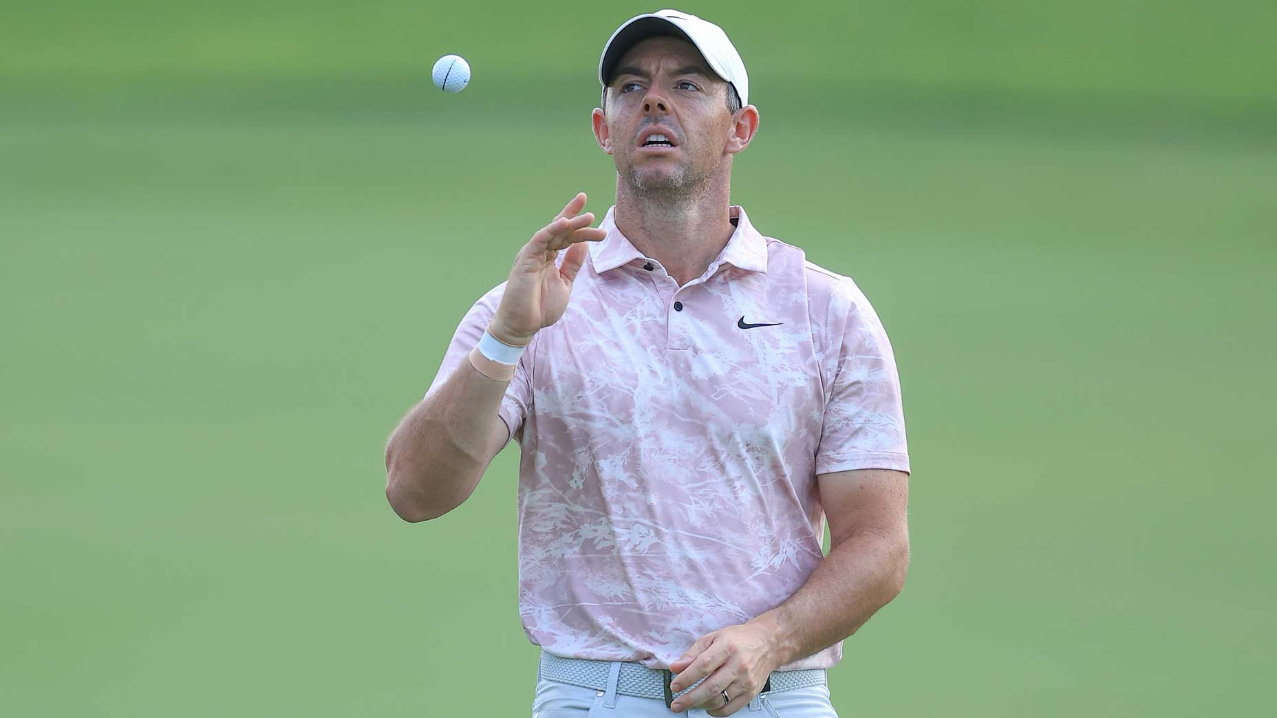 Rory McIlroy tosses golf ball in air during 2023 DP World Tour Championship