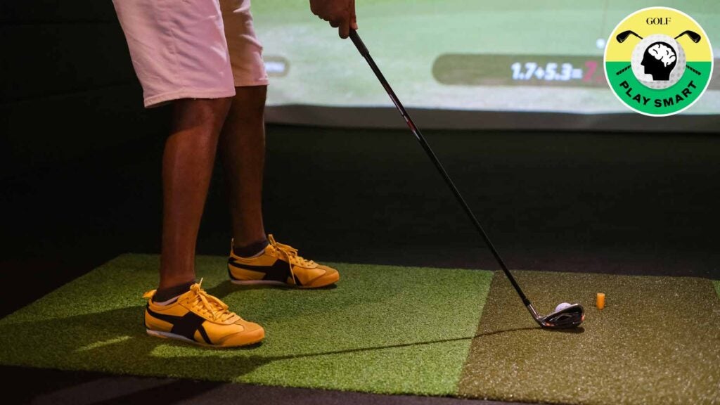 golfer lines up to hit golf ball on indoor simulator