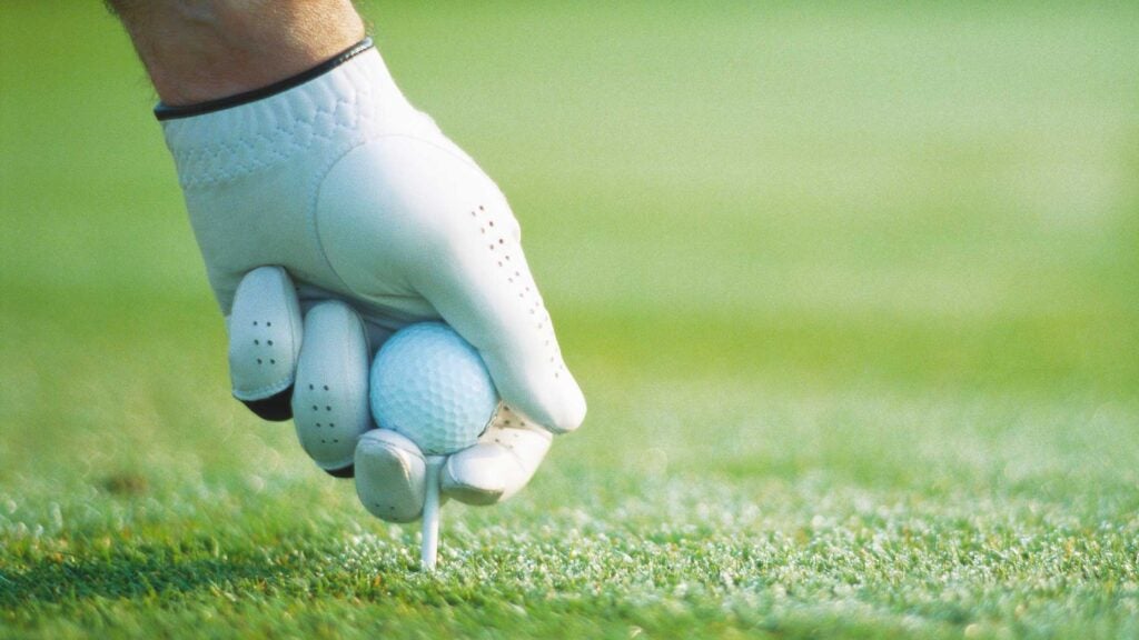 a golfer tees up a golf ball